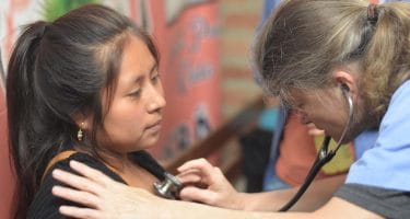 IMR volunteer examining a patient with a stethoscope in Ecuador