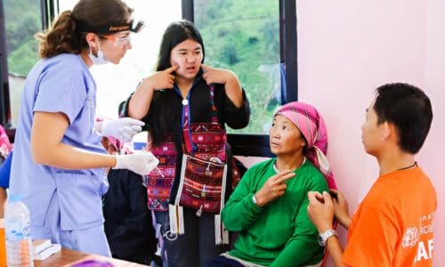 Photo of a volunteer interpreter asking questions of a patient to interpret for a doctor.