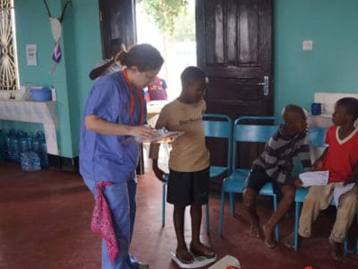 non-medical volunteer weighing a patient, Tanzania 2014